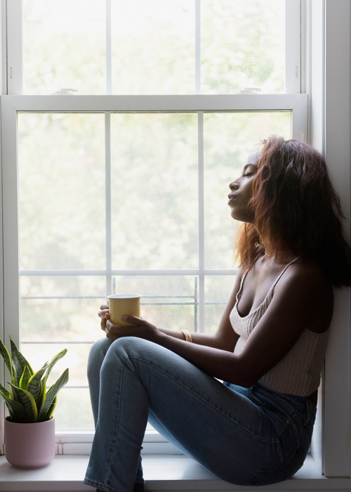 woman sitting by window holding a cup of tea