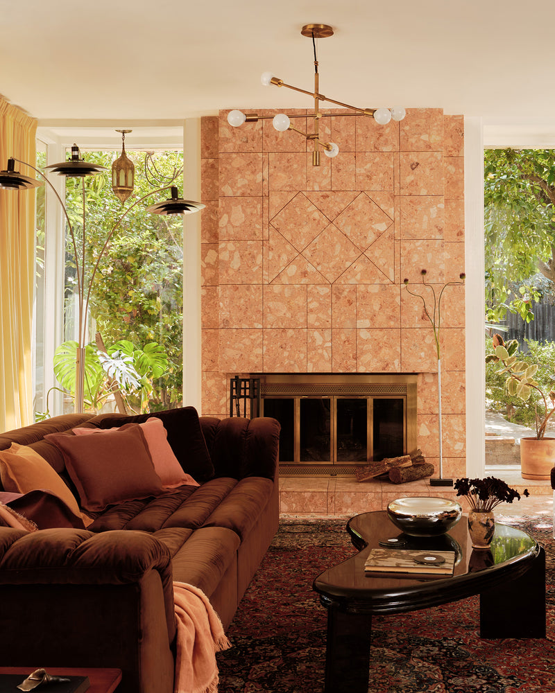 Living room with a brown sectional sofa covered with 100% French flax linen soft furnishings in terracotta, pink clay and cacao; plus a coffee table, and stone fireplace
