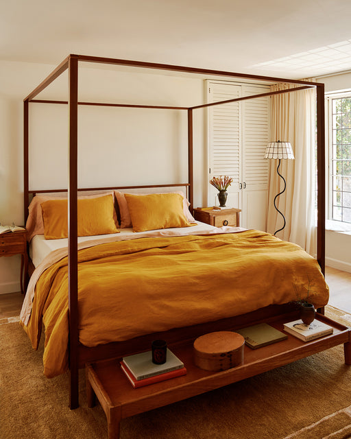Bedroom with a wooden canopy bed and 100% french flax linen bedding in turmeric, terracotta and creme.