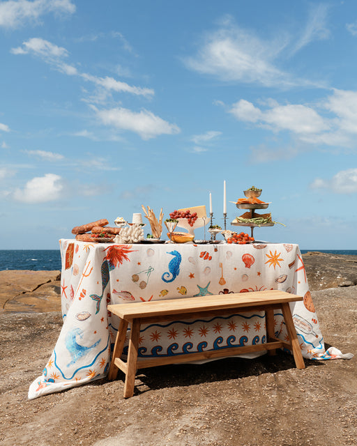 Outdoor table setting with a sea-themed tablecloth by the ocean