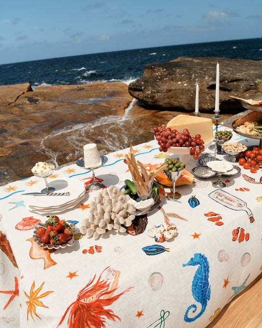 Table set with food and drinks on a scenic coastal background