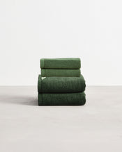 A stack of two, organic cotton terry hand towels and two face washers in a moss green shade. - view