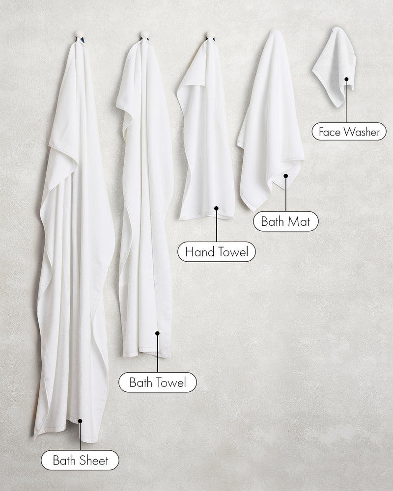Five white linens from Bed Threads hang left to right—bath sheet, bath towel, hand towel, bath mat, and Crisp White 100% Cotton Terry Face Washers (set of two)—arranged largest to smallest.