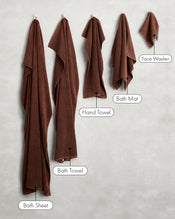 Two Espresso 100% Cotton Terry Face Washers by Bed Threads hang on hooks against a light wall—crafted from soft, absorbent terry that's gentle on the skin. - view