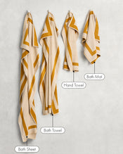 Two Crème & Turmeric Two-Toned 100% Cotton Terry Hand Towels by Bed Threads hang on the wall, showcasing their plush 650GSM fabric and quick-drying performance. - view