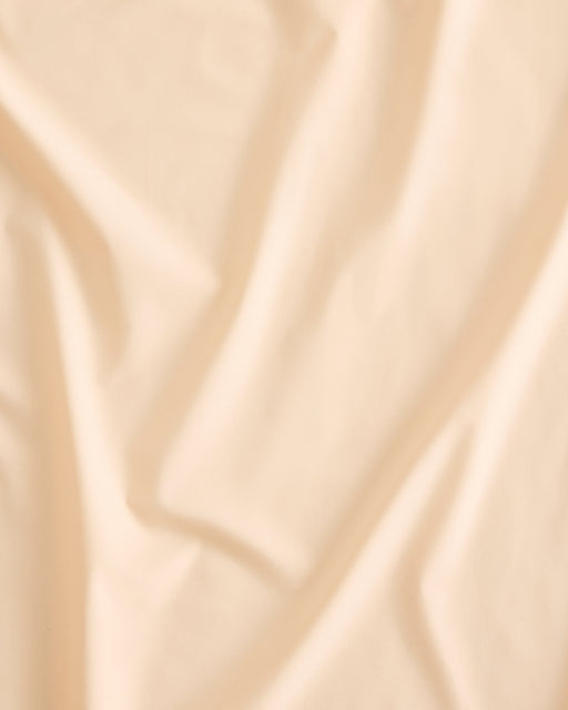 A close-up of the Bed Threads Vanilla 100% Organic Cotton Bedding Set showcases soft, gentle folds and creases, giving it a smooth yet slightly textured look.