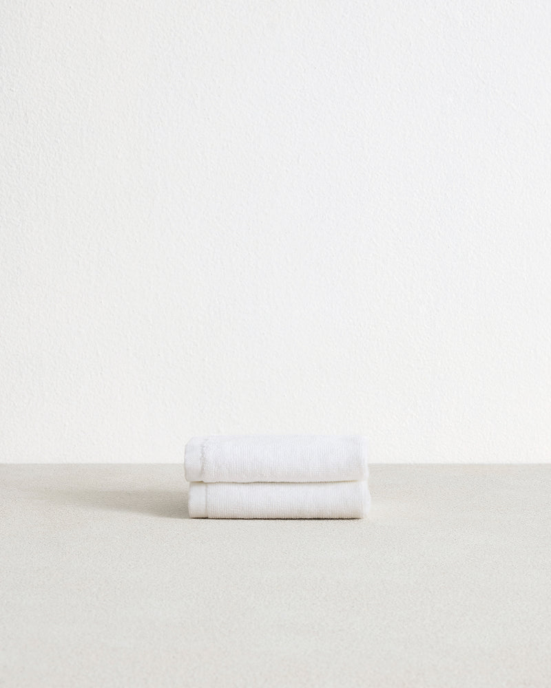 The Bed Threads Crisp White 100% Cotton Terry Face Washers (Set of Two) are stacked on a light surface against a plain white background—soft, absorbent, and gentle on skin.