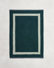 The Forest & Sage Two-Toned 100% Cotton Terry Bath Mat by Bed Threads features a rectangular dark green design with a lighter green border, shown on a light textured surface. - view