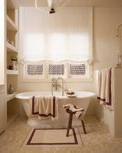 Neutral bathroom with freestanding bath tub and cotton terry towels in a creme colour with cacao border. - view