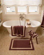 Close up of a freestanding bath tub with cotton terry towels in a cacao colour with creme border. - view