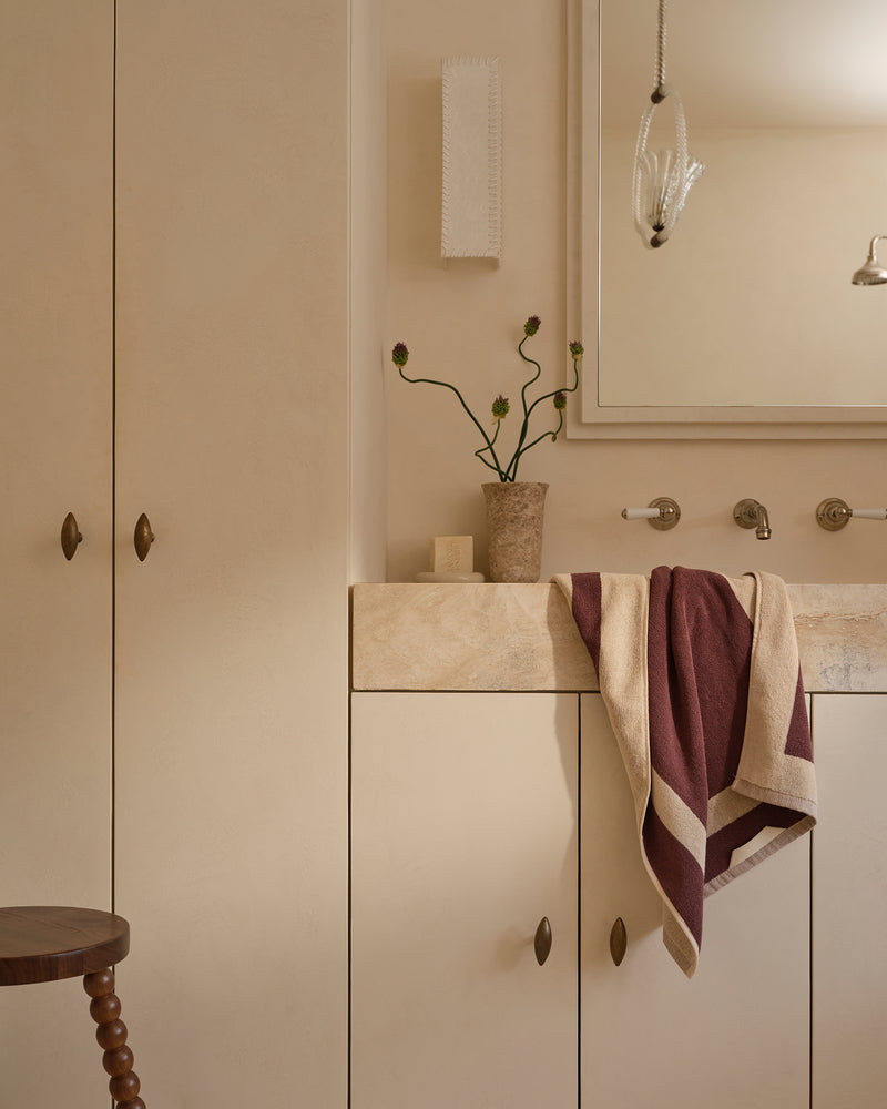 Neutral bathroom with cotton terry hand towel in cacao & creme hanging near sink.