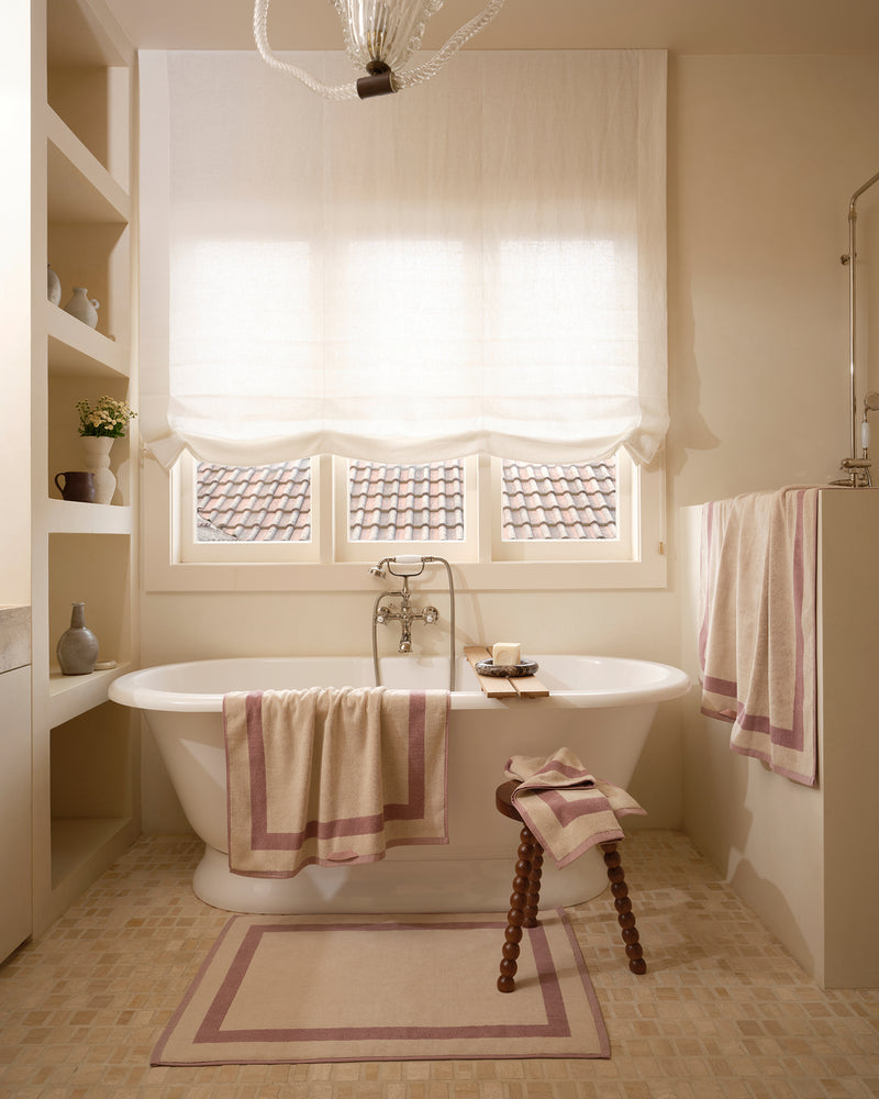 Neutral bathroom with freestanding bath tub and cotton terry towels in a creme colour with lavender border.