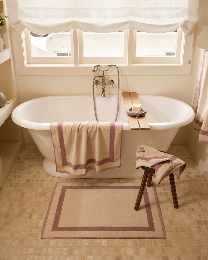 Close up of a freestanding bath tub with cotton terry towels in a creme colour with lavender border.