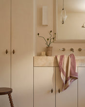 Neutral bathroom with cotton terry hand towel in lavender and creme hanging near sink. - view