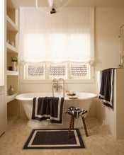 Neutral bathroom with freestanding bath tub and cotton terry towels in a charcoal colour with oatmeal border. - view