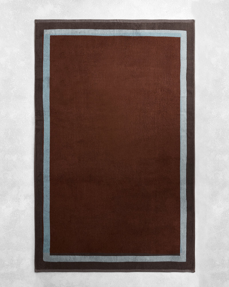 The Cacao & Lagoon Two-Toned 100% Cotton Terry Bath Sheet Bundle by Bed Threads features a dark brown center with a light blue stripe and dark gray border—ideal for a coordinated look when paired with plush bath towels.