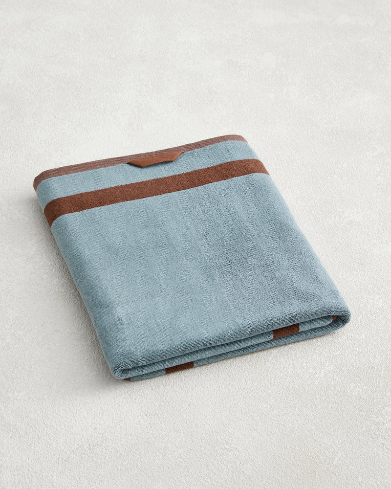 The Bed Threads Cacao & Lagoon Two-Toned 100% Cotton Terry Bath Sheet features plush, quick-drying cotton in light blue with brown stripes—ideal for a stylish and practical addition to your bath routine.