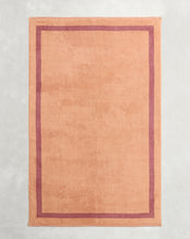 A set of Bed Threads Terracotta & Pink Clay Two-Toned 100% Cotton Terry Bath Sheets, featuring a contrasting border, is displayed flat on a light gray textured background. - view