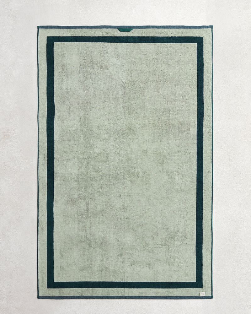 The Bed Threads Forest & Sage Two-Toned 100% Cotton Terry Bath Sheet Bundle features a rectangular, light gray-green luxury towel with a dark green double border, shown flat on a light surface.