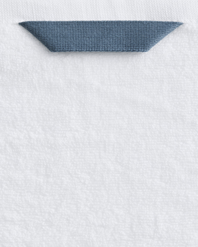 A close-up of the Bed Threads Crisp White 100% Cotton Terry Bath Sheet Bundle, showing a dark blue fabric loop neatly sewn onto the top edge for easy hanging.