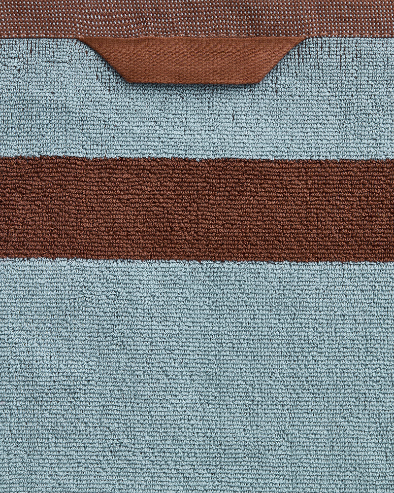 Close-up of the Bed Threads Cacao & Lagoon Two-Toned 100% Cotton Terry Bath Sheet Bundle, featuring plush light blue textured fabric, a horizontal brown stripe, and a brown loop at the top edge.