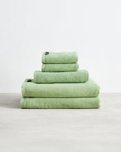 The Bed Threads Apple 100% Cotton Terry Bath Sheet Bundle features four highly absorbent, light green towels in various sizes, neatly stacked on a light surface against a plain white background. - view