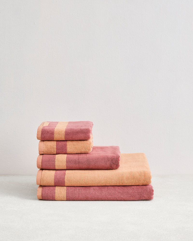 The Bed Threads Terracotta & Pink Clay Two-Toned 100% Cotton Terry Bath Sheet Bundle features four luxury bath sheets stacked by size, adding spa-like elegance to any bathroom décor.