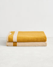 The Bed Threads Crème & Turmeric Two-Toned 100% Cotton Terry Bath Sheets (Set of Two) showcase a mustard yellow towel with a white stripe and a beige towel with a mustard yellow stripe—perfect for upgrading your spa-day essentials. - view
