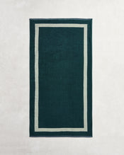 A rectangular dark green rug with a beige double border, set on a light surface, creates a serene space—perfect for pairing with the Forest & Sage Two-Toned 100% Cotton Terry Bath Towel Bundle from Bed Threads. - view