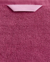 A close-up of the Bed Threads Berry 100% Cotton Terry Bath Towel shows its textured, plush pink fabric and a matching hanging loop at the top. - view
