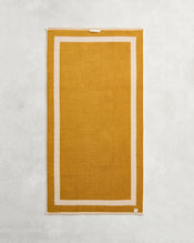 The Bed Threads Crème & Turmeric Two-Toned 100% Cotton Terry Bath Towel, 650GSM, is laid flat to highlight its plush texture and elegant beige border. - view