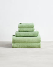 A neatly stacked Bed Threads Apple 100% Cotton Terry Bath Towel Bundle of four light green, highly absorbent towels in varying sizes, arranged largest to smallest, set against a plain white background. - view