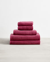 A neatly stacked Bed Threads Berry 100% Cotton Terry Bath Towel Bundle—five folded towels in varying sizes, largest to smallest, displayed against a plain white background. - view