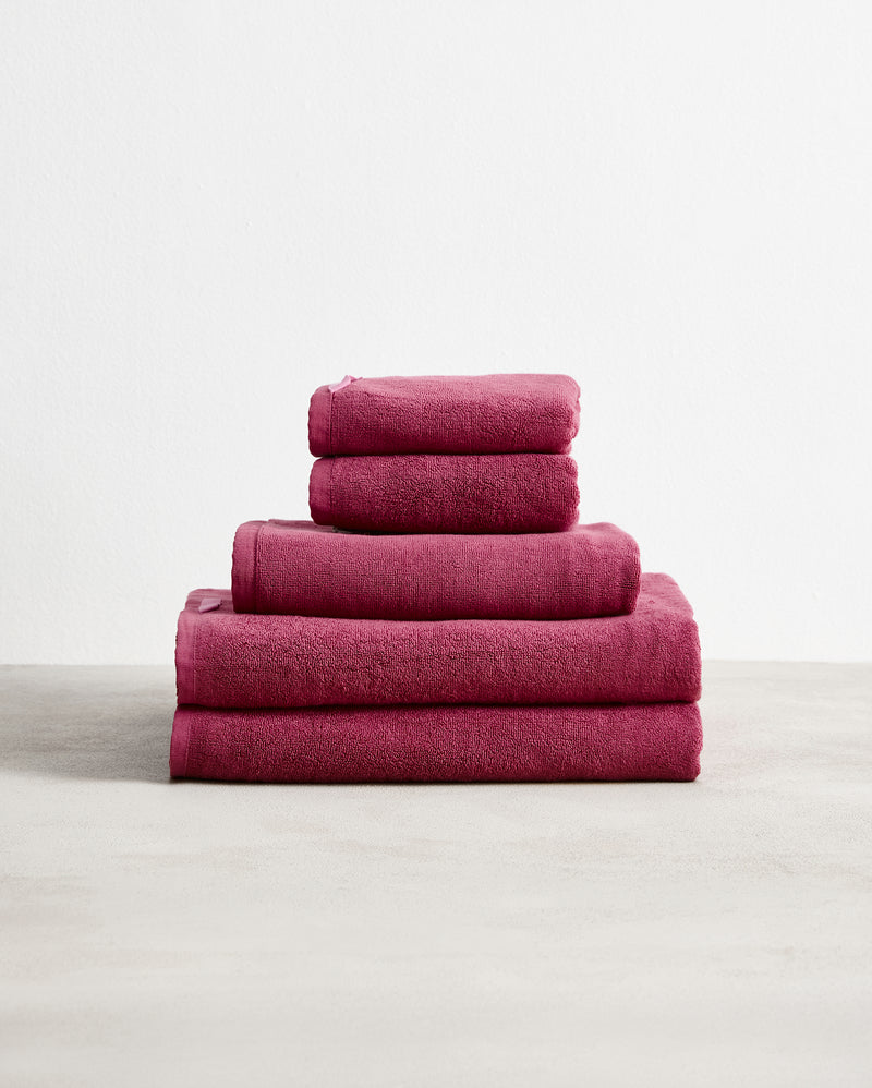 A neatly stacked Bed Threads Berry 100% Cotton Terry Bath Towel Bundle—five folded towels in varying sizes, largest to smallest, displayed against a plain white background.