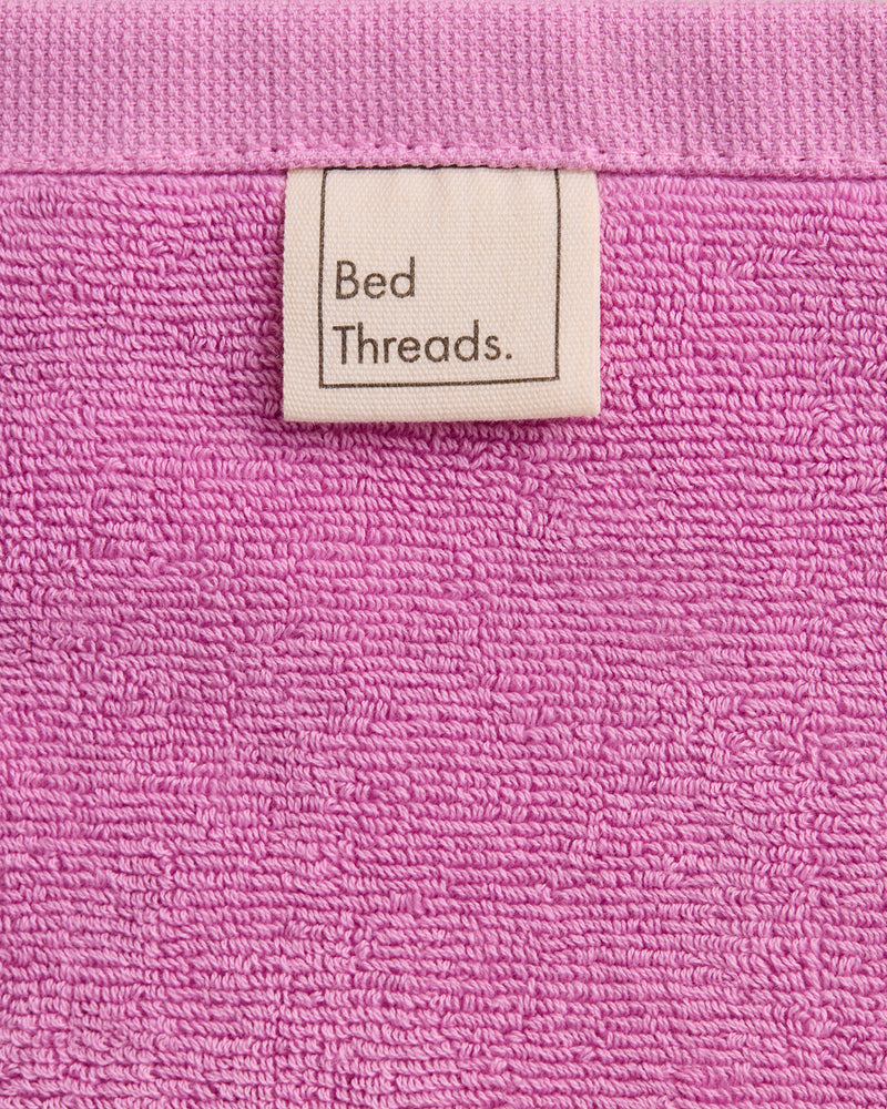 A close-up of Bubblegum 100% Cotton Terry Face Washers by Bed Threads, featuring a beige Bed Threads label and crafted from soft, absorbent terry that's gentle on skin—perfect for daily cleansing. Set includes two face washers.