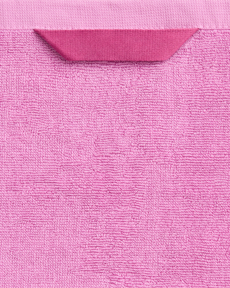 A close-up of the Bubblegum 100% Cotton Terry Bath Towel by Bed Threads, crafted from plush 650GSM cotton terry with a textured pink finish and a darker pink fabric tag near the top edge.