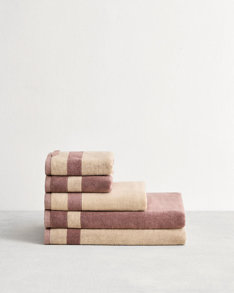 Stack of cotton terry bath towels in reversible colours creme and lavender. 