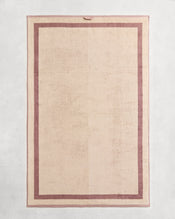 Flat cotton terry bath sheet on a grey background in a creme colour with a lavender border. - view
