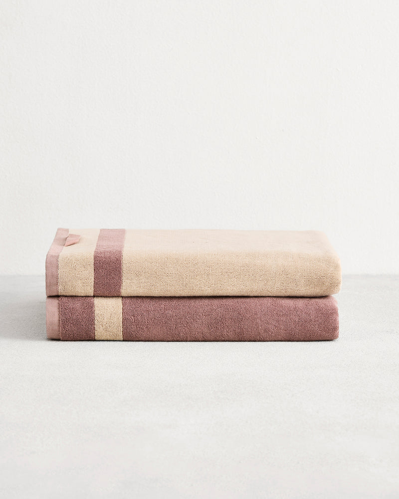 Stack of two cotton terry bath sheets in reversible colours creme and lavender. 