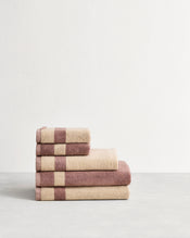 Stack of cotton terry towels in reversible colours creme and lavender.  - view