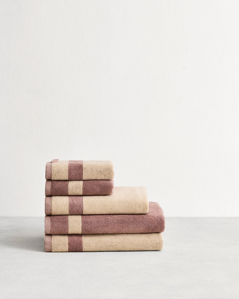 Stack of cotton terry towels in reversible colours creme and lavender. 