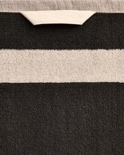 Close-up of a cotton terry bath towel in a charcoal colourway with an oatmeal border. - view