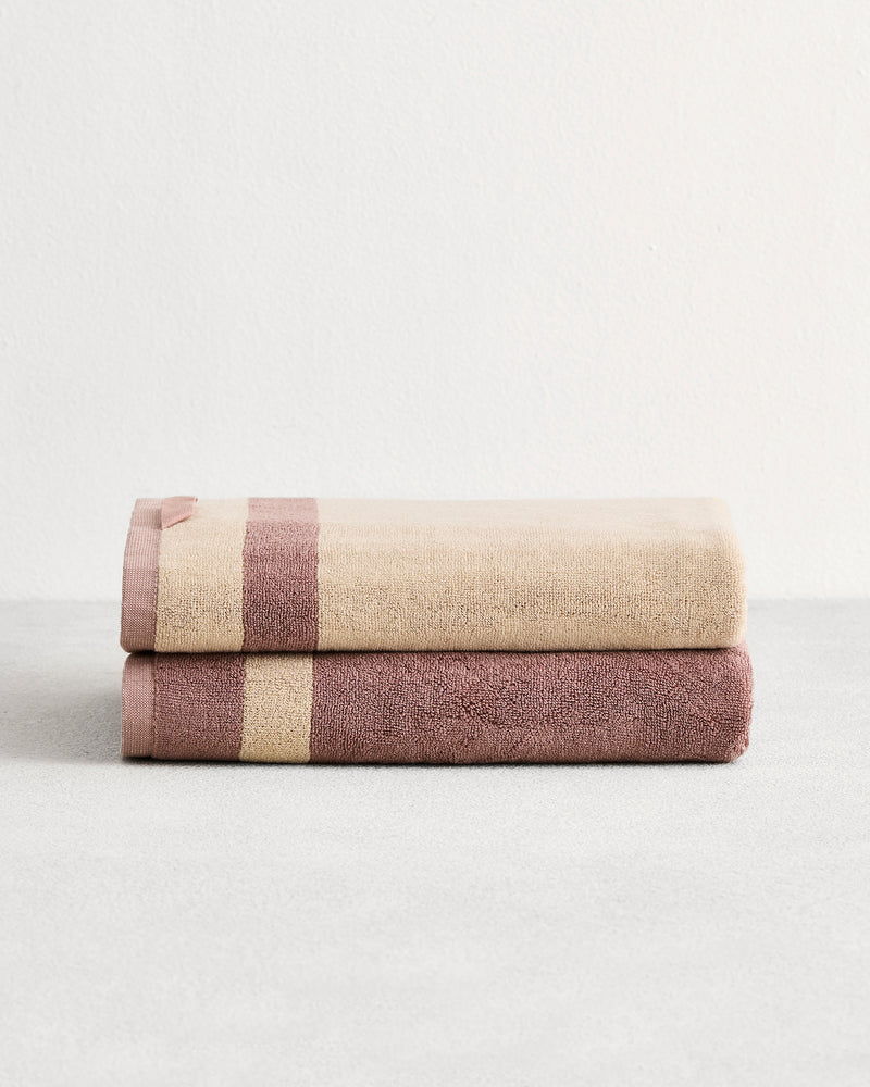 Stack of two cotton terry bath towels in reversible colours creme and lavender. 