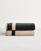 Stack of two cotton terry bath towels in reversible colours oatmeal and charcoal. - view
