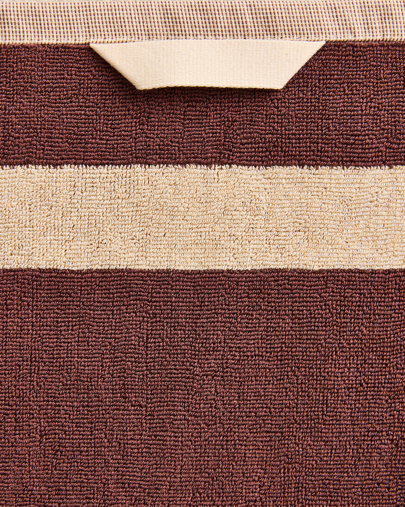 Close-up of a cotton terry towel in a cacao colourway with a creme border.