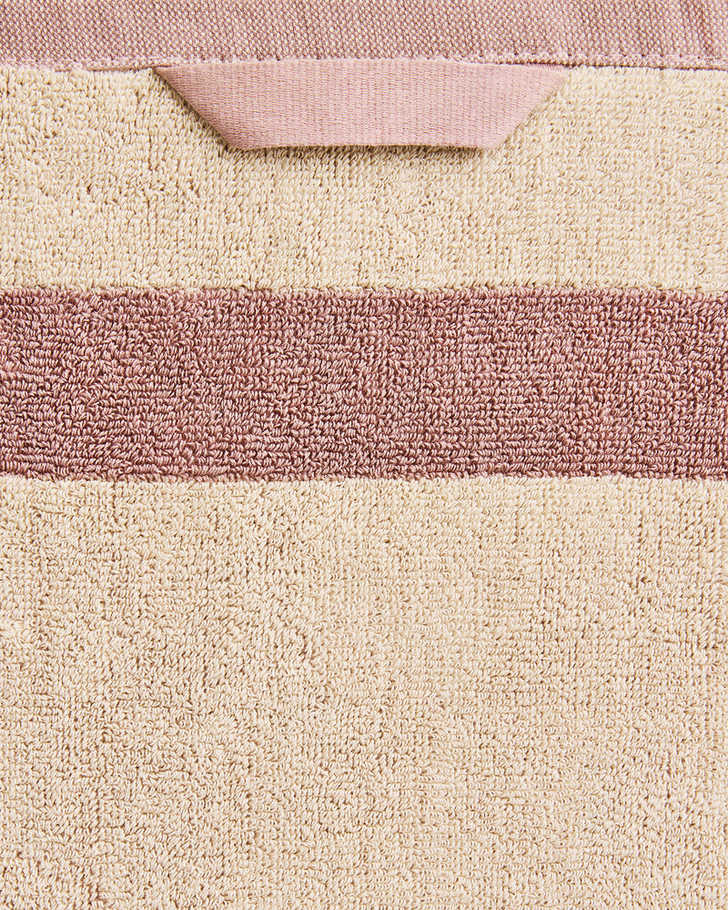 Close-up of a cotton terry bath towel in a creme colourway with a lavender border.
