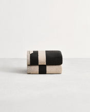 Stack of two cotton terry hand towels in reversible colours oatmeal and charcoal.  - view