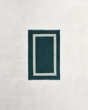 A Forest & Sage Two-Toned 100% Cotton Terry Hand Towel by Bed Threads, featuring a plush 650GSM texture and double border design, is displayed on a light, textured surface. - view
