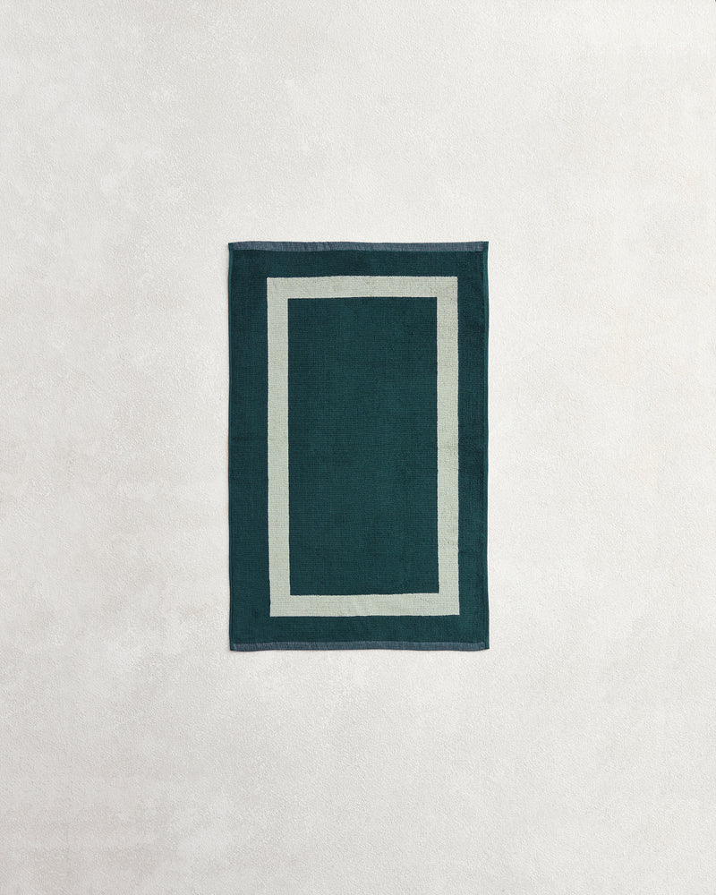 A Forest & Sage Two-Toned 100% Cotton Terry Hand Towel by Bed Threads, featuring a plush 650GSM texture and double border design, is displayed on a light, textured surface.