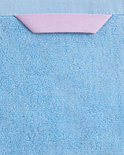 A close-up of the Sky 100% Cotton Terry Bath Sheet by Bed Threads, featuring blue textured cotton and a small folded pink fabric detail near the top edge, highlights these luxury bathroom towels. - view